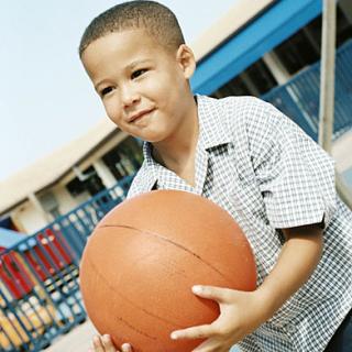 child holding a basketball on the playground