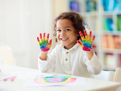 child smiling with paint on hands 