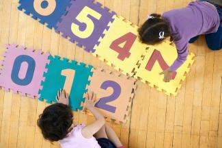 children playing with foam mats with letters and numbers
