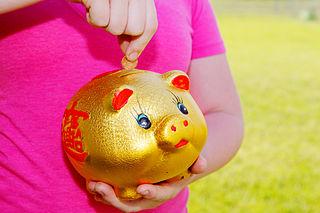 girl putting money in piggy bank