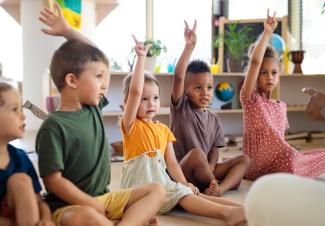 students raising hands in classroom