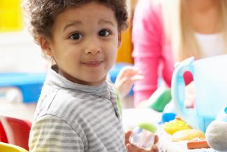 little boy in a preschool setting smiling at the viewer